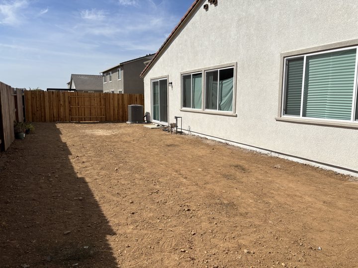 Bare dirt backyard before the design